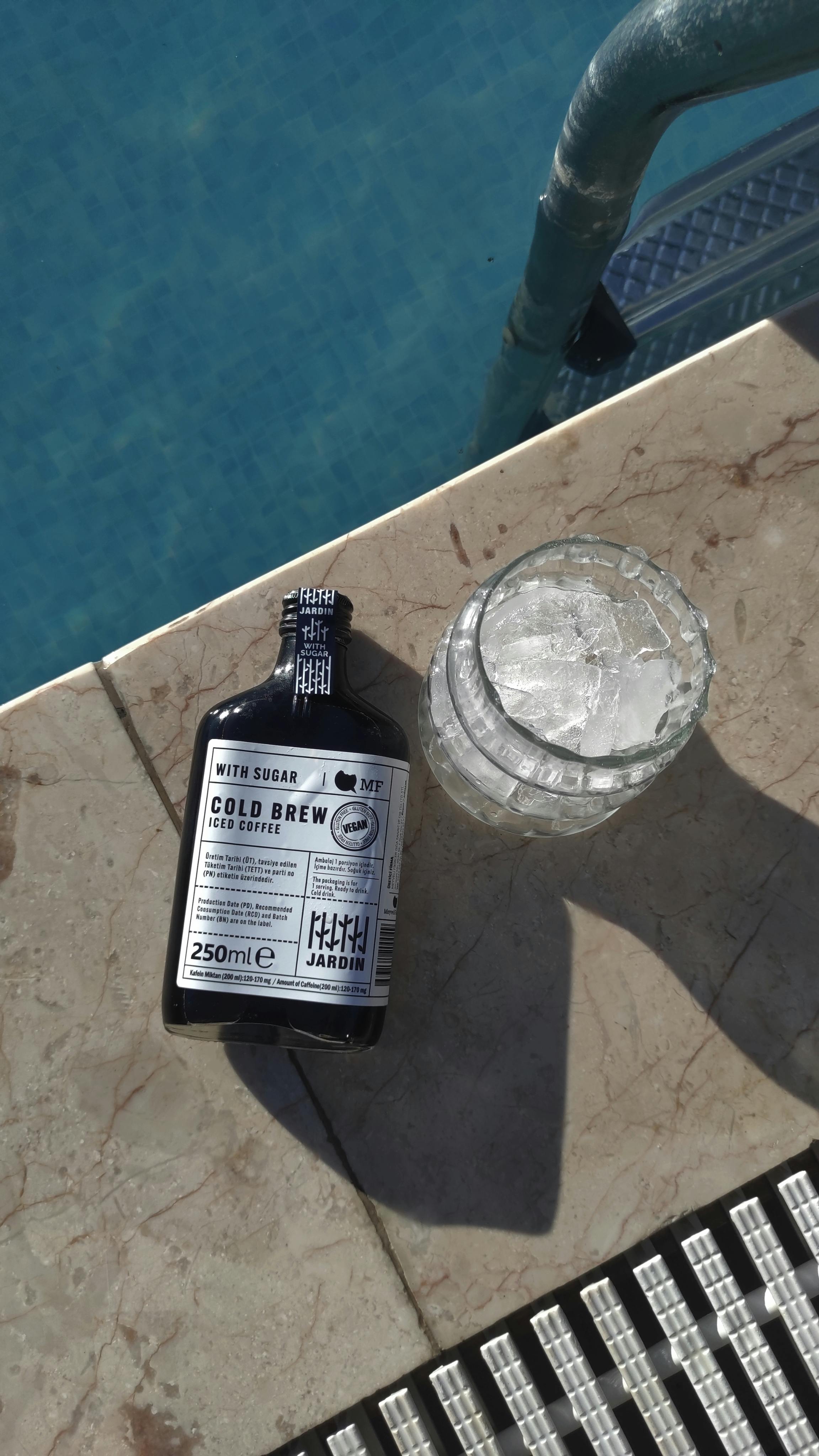 Free Chilled bottle of cold brew coffee with ice by a pool in Sapanca, Türkiye. Refreshing summer vibe. Stock Photo