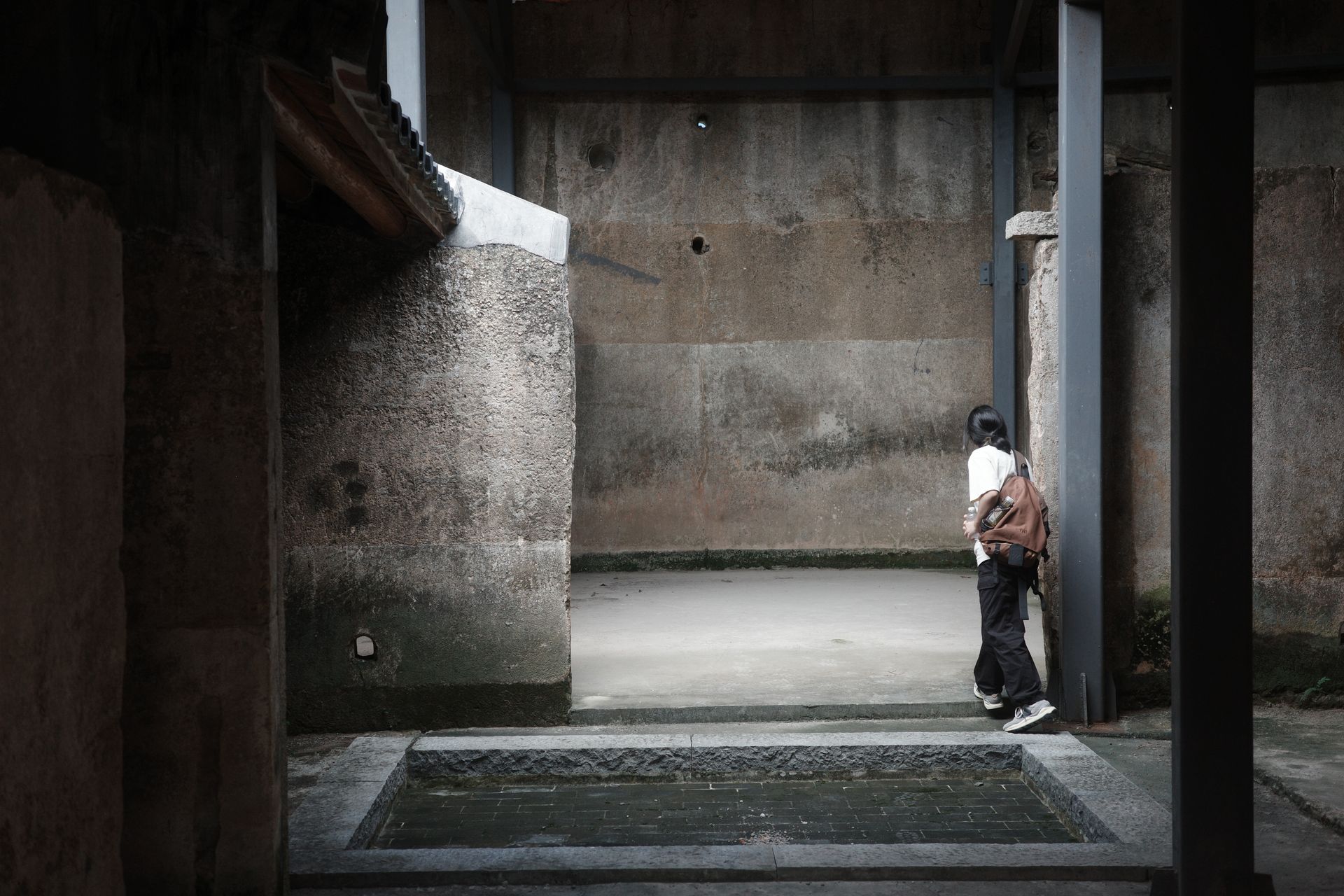 A Woman Standing in an Alley between Concrete Walls