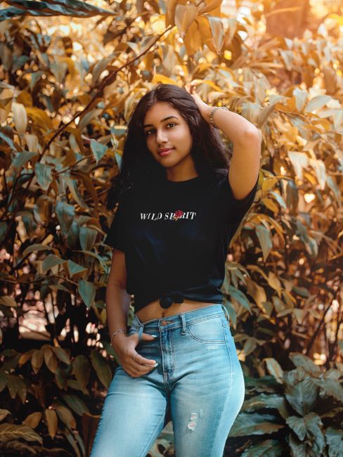 Portrait of a young woman posing confidently amidst lush greenery.