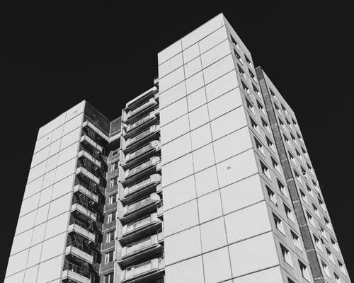 Free A striking black and white photo of a modern high-rise building's facade, captured from a low angle. Stock Photo
