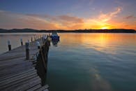 宁静的日落映照在平静的大海上，木制码头和船只点缀其间，非常适合放松和激发旅行灵感