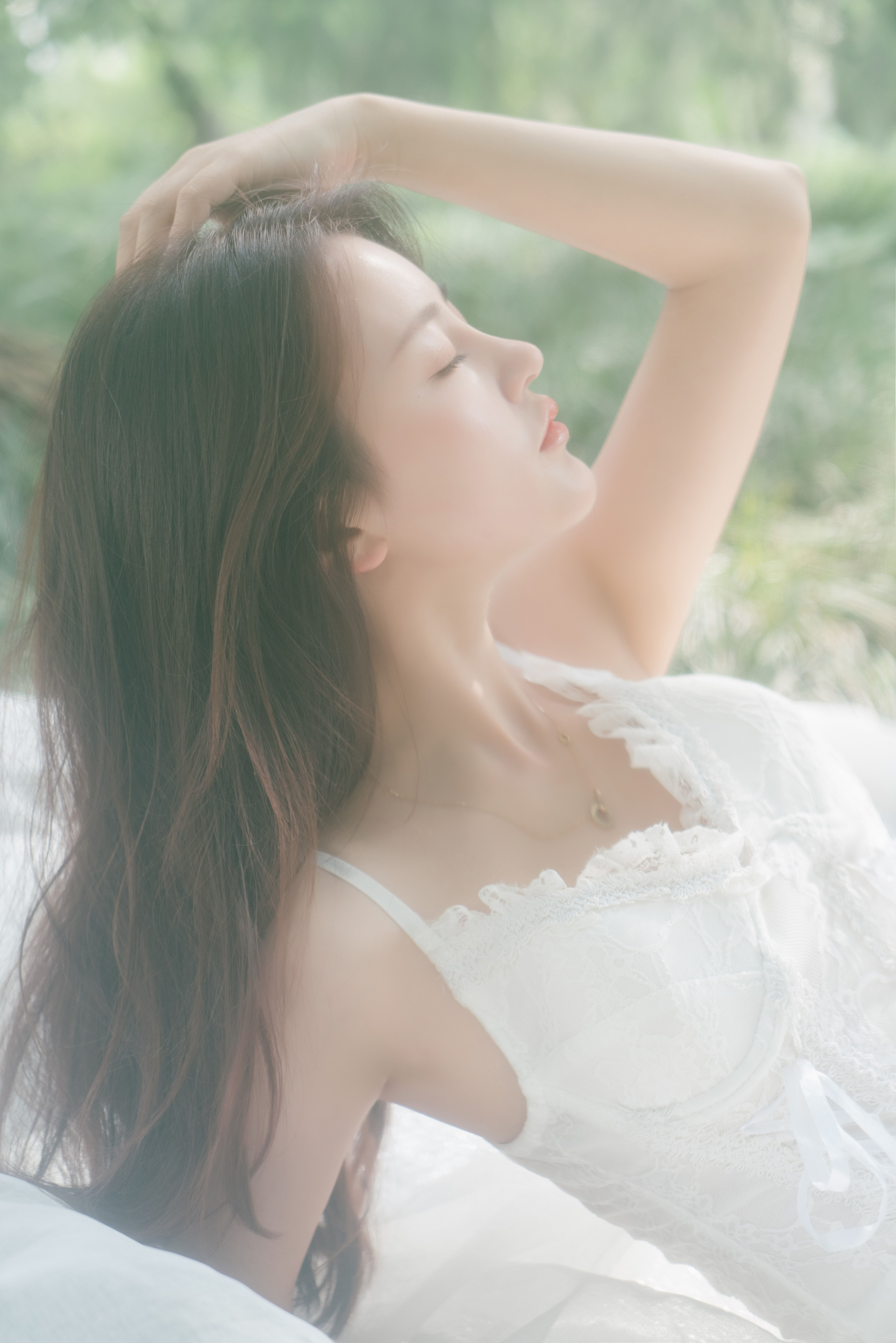 Elegant fashion portrait of a woman in lace lingerie enjoying nature's tranquility.