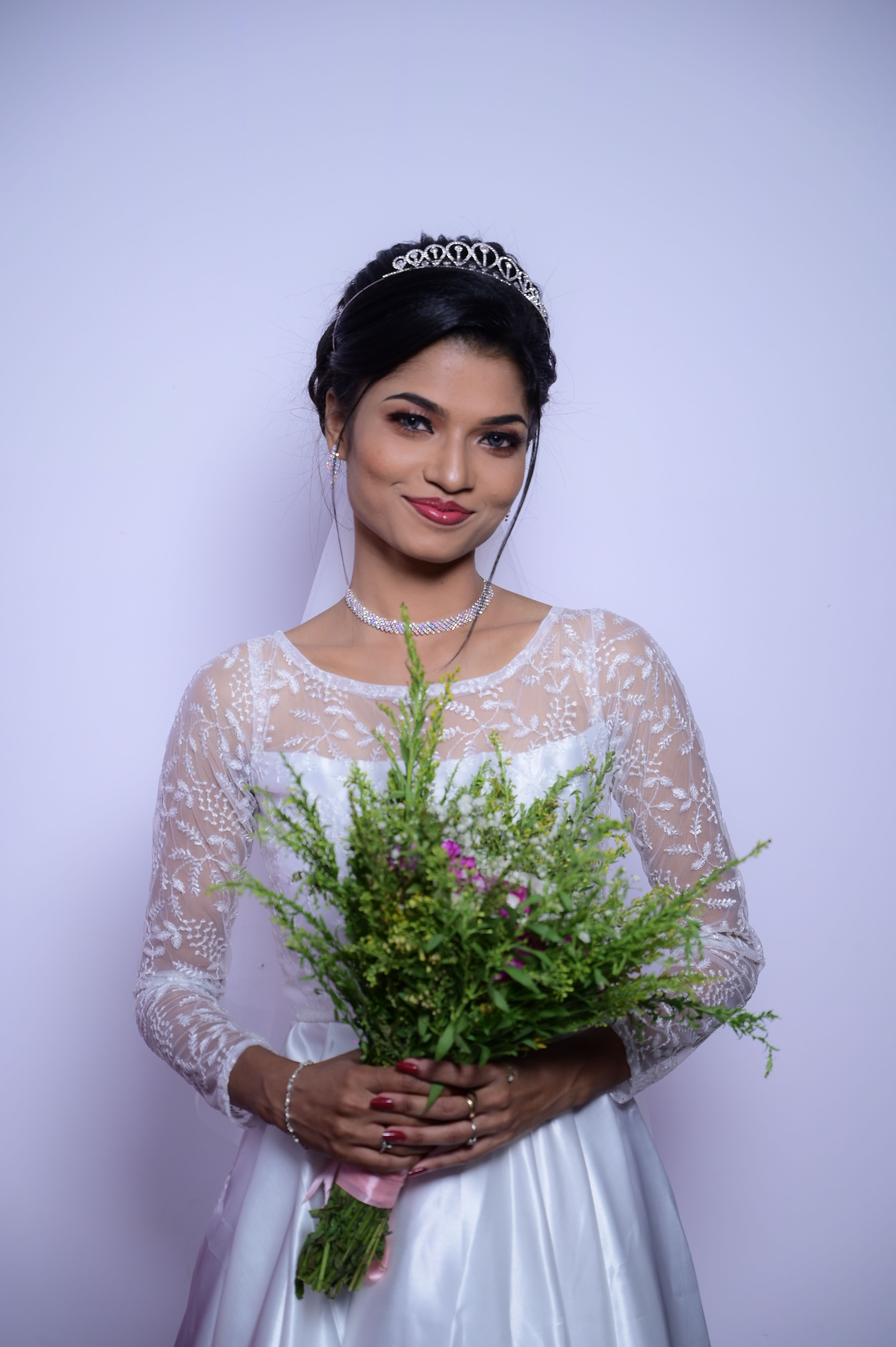Beautiful bride in white wedding dress holding a bouquet, smiling radiantly.
