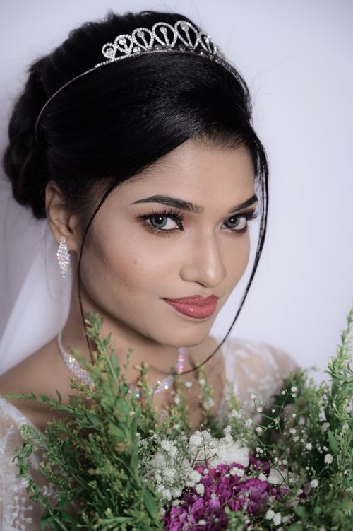 Free A beautiful bride holding a vibrant bouquet, adorned in wedding attire with a serene expression. Stock Photo