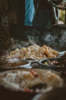 A warm, atmospheric shot of steaming Asian cuisine bowls in a rustic setting.