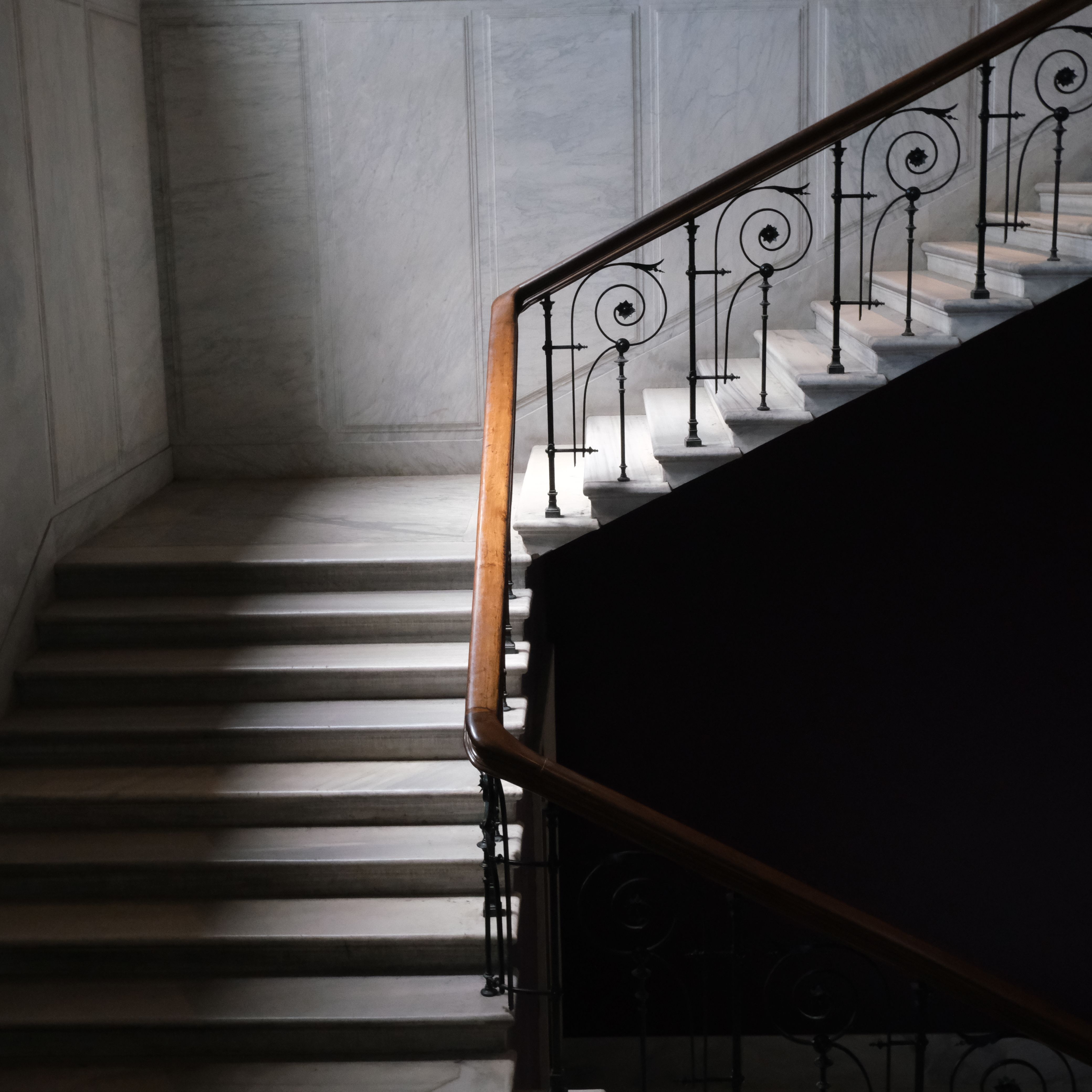 Sophisticated marble staircase with ornate iron handrail, perfect for architectural themes.