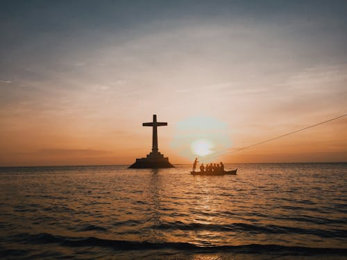 Photo Of Cross In An Ocean During Dawn