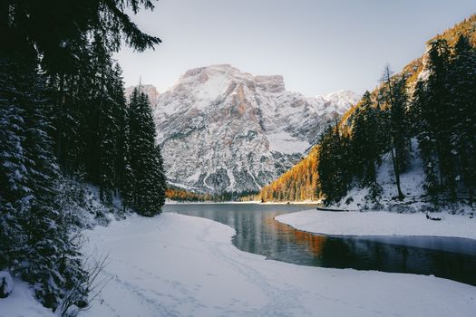 A stunning winter scene of snow-covered mountains and a peaceful river in a forested valley.