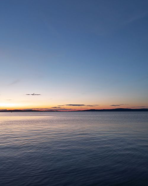 Free Peaceful ocean view at sunset with calm waters and clear sky. Perfect for relaxation and nature themes. Stock Photo