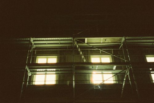 Free Photo of an apartment building with scaffolding and lit windows at night. Stock Photo