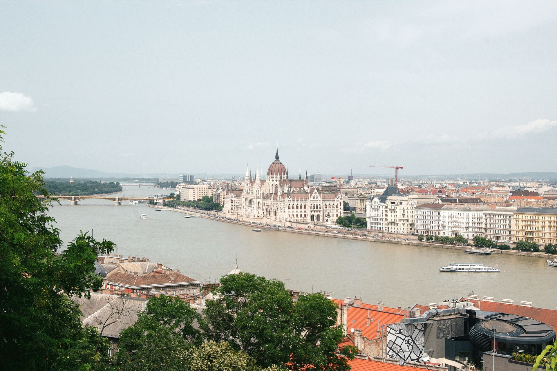 Aerial photograph of Budapest's iconic Hungarian Parliament Building along the Danube River on a sunny day.