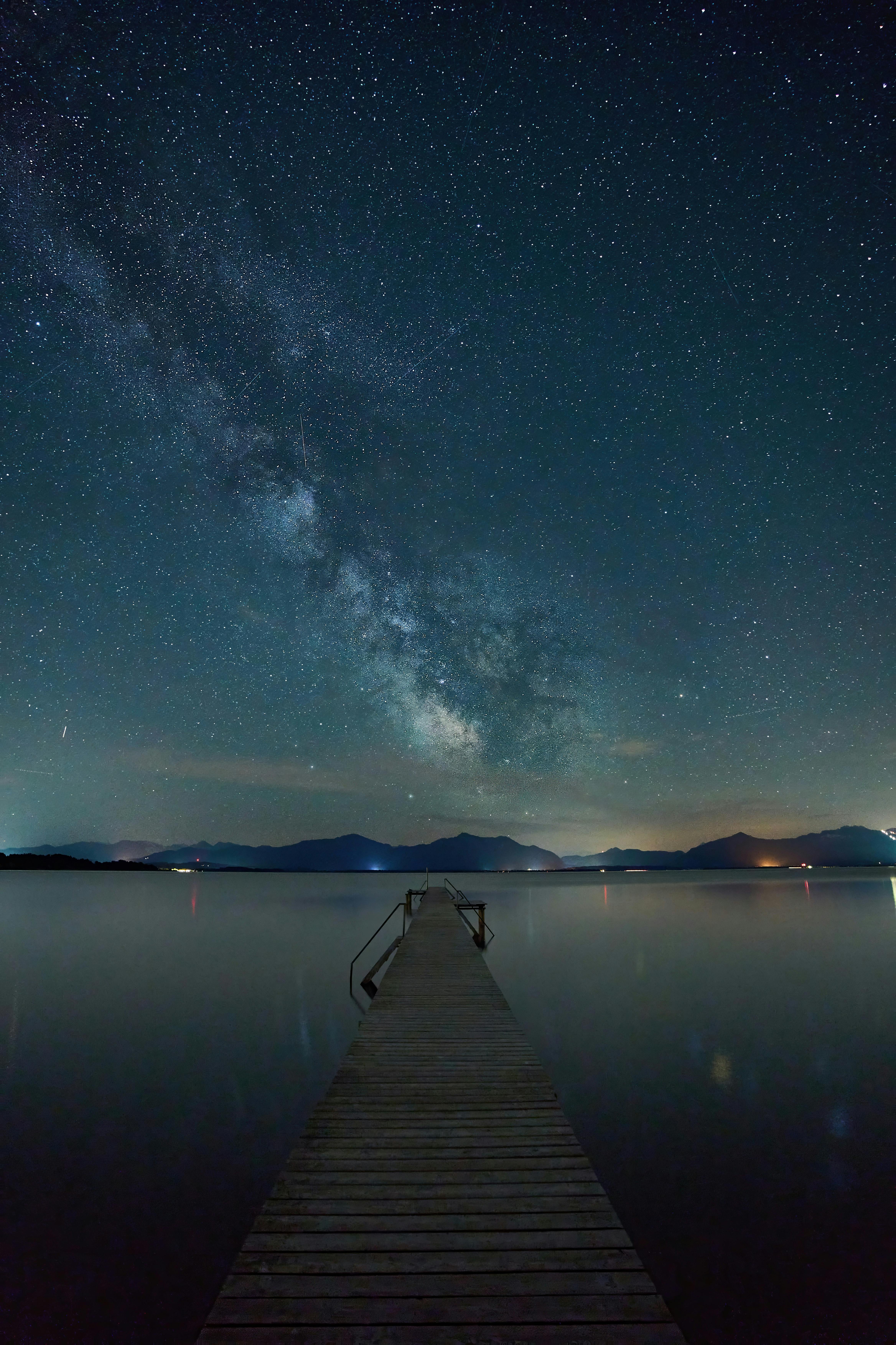 Milky Way over a calm lake and pier in Seeon-Seebruck, Germany.