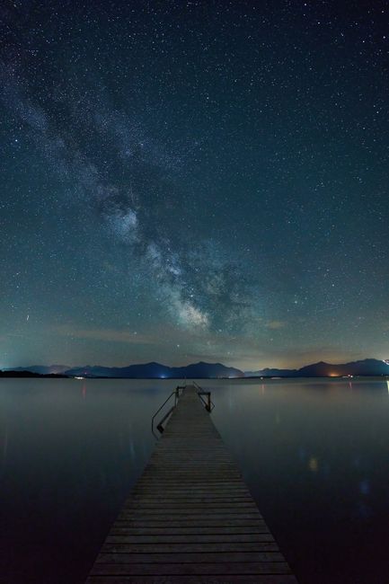 Milky Way over a calm lake and pier in Seeon-Seebruck, Germany.