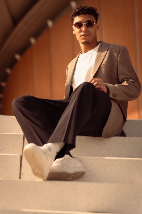 Free Fashionable man in sunglasses posing stylishly on urban steps in a modern city setting. Stock Photo