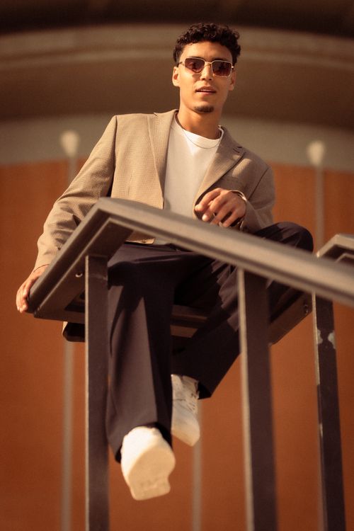 Free Fashionable man posing on staircase steps with sunglasses and trendy outfit in warm sunlight. Stock Photo