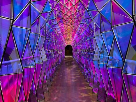 Explore a mesmerizing geometric tunnel illuminated with vibrant purple and blue hues creating stunning reflections.