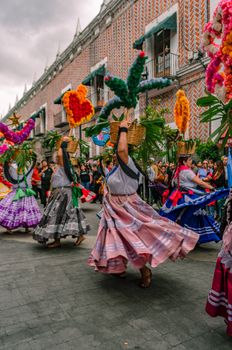 Vibrant street dance in Puebla, Mexico, featuring women in traditional dresses celebrating a cultural festival.