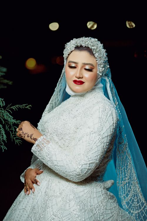 Free Portrait of a beautiful bride in a white gown with intricate veil under night lights. Stock Photo