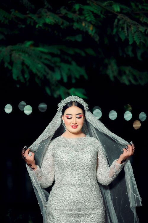 Free Stylish portrait of a bride in a shimmering gown and veil, captured at night. Stock Photo