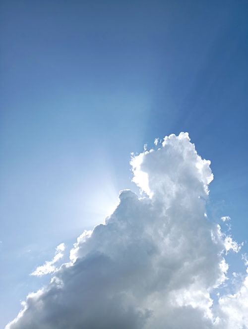 Free Captivating view of a cumulus cloud with sunlight peeking through, set against a clear blue sky. Stock Photo