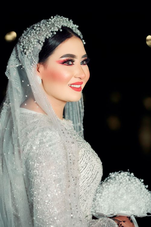 Free Beautiful bride in sparkling wedding dress holding bouquet with a joyful smile. Stock Photo
