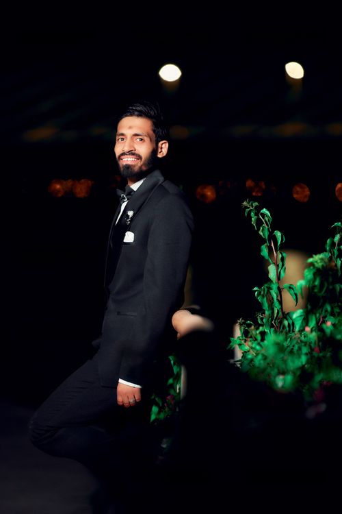 Free Smiling man in a suit posing against a dark background with lights. Stock Photo