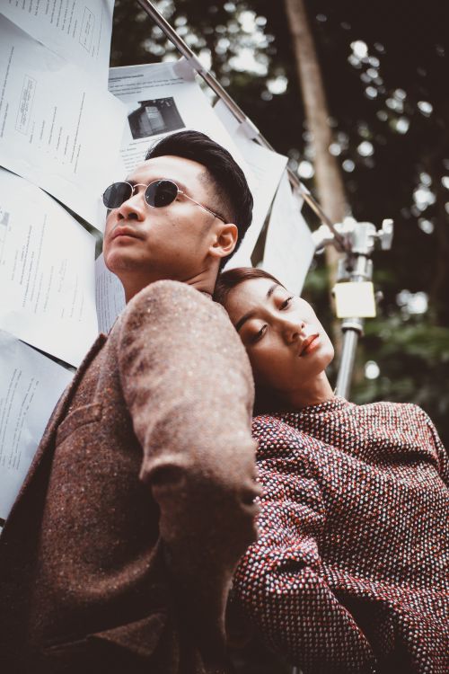 Free Fashionable Asian couple posing outdoors with relaxed expressions and stylish outfits. Stock Photo