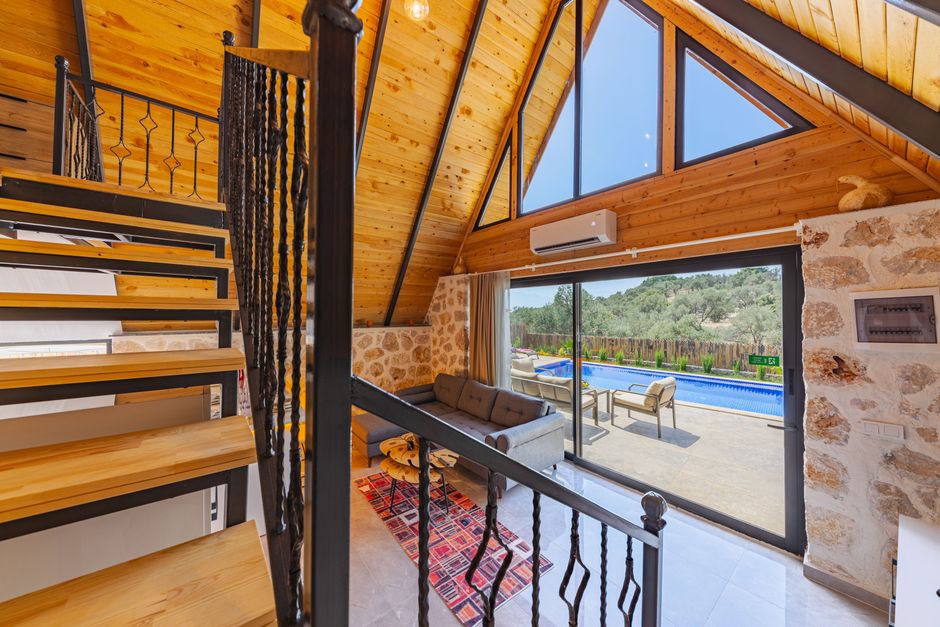 Holiday let property interior with staircase, sofa, and outdoor swimming pool view.