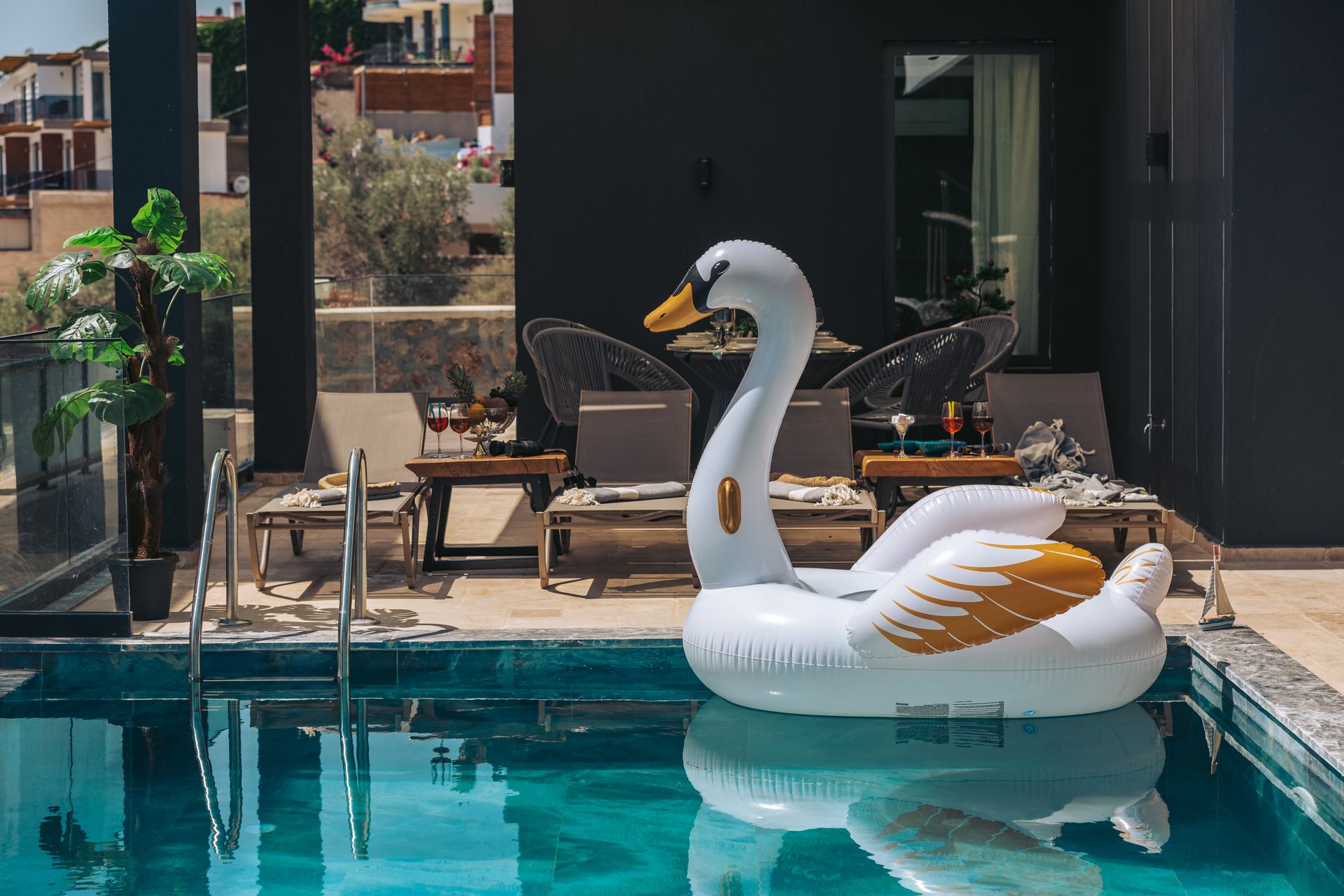 A serene luxury resort pool featuring a large inflatable swan and sun loungers.