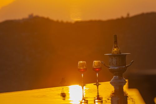 Free Wine bottle and glasses on a table during a beautiful sunset, creating a romantic ambiance. Stock Photo