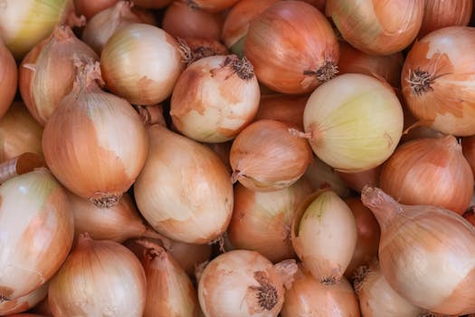A close-up of fresh brown onions piled together, showcasing their natural texture.