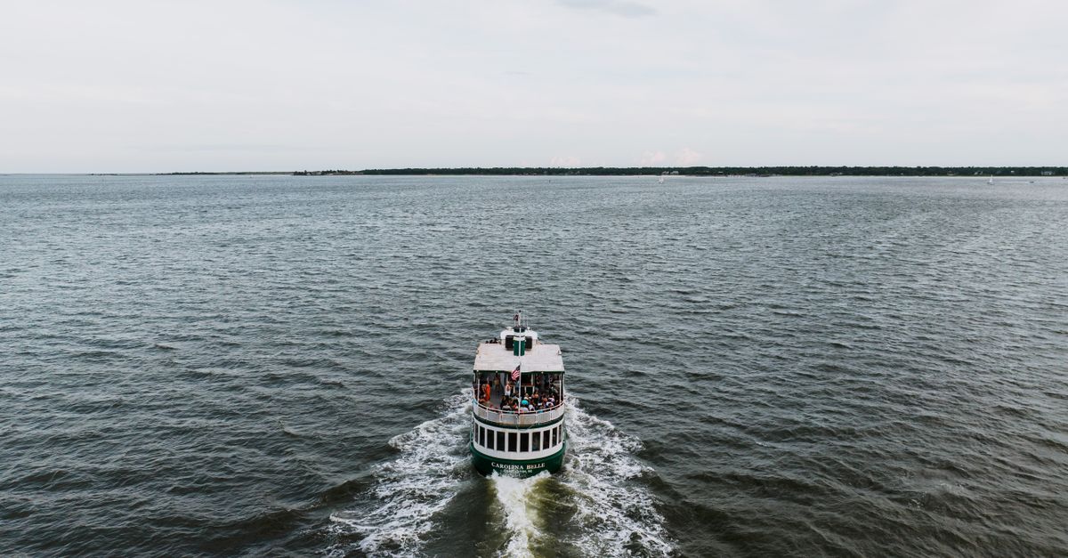 A tourist ferry cruises through Charleston Harbor with passengers enjoying the scenic view.