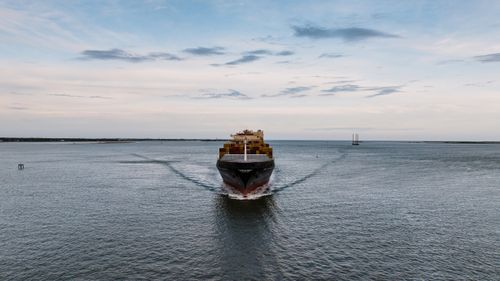 Free A large container ship sails through the ocean towards Charleston Harbor under a cloudy sky. Stock Photo
