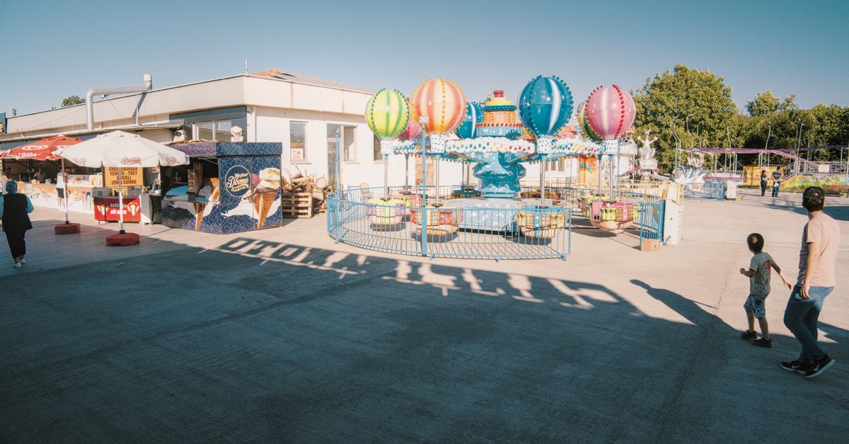 Colorful carnival scene with balloon ride and visitors enjoying a sunny day outdoors.
