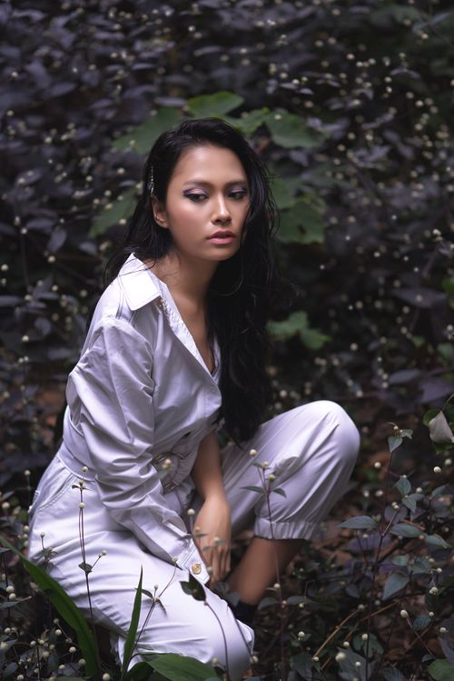 Free Elegant fashion model poses amidst dense tropical foliage in West Java, Indonesia. Stock Photo