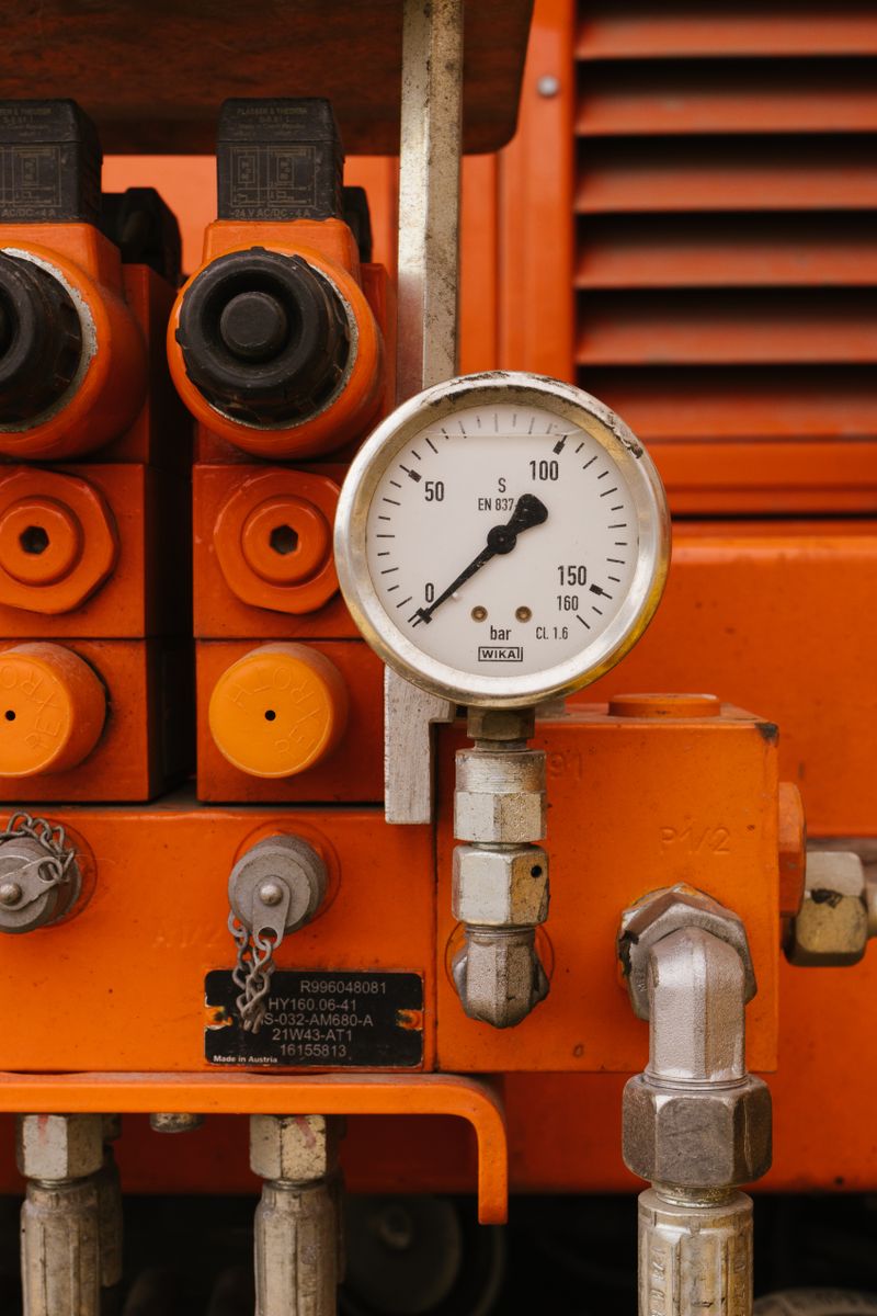 Pressure gauge on orange hydraulic machinery