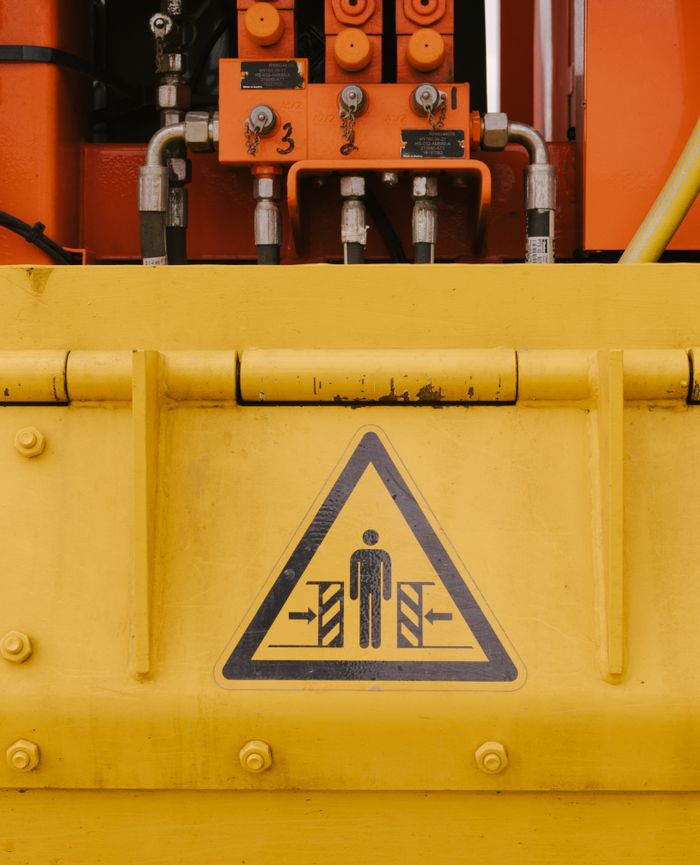 Close-up of industrial machine with a warning sign indicating potential hazards