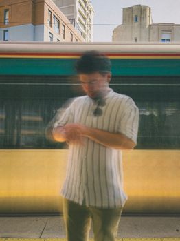 Blurred motion photo of a man checking watch at Istanbul station with train in background.