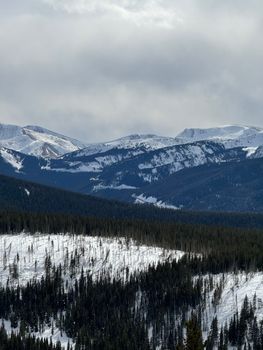 Discover the serene beauty of the snow-covered Rocky Mountains in Colorado, USA, under cloudy skies.