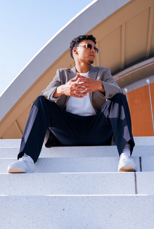 Free Confident man in fashionable outfit sitting at Berlin Congress Hall steps, exuding elegance and style. Stock Photo