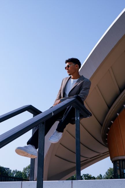 Young man posing stylishly by a distinctive architectural structure in Berlin, Germany.