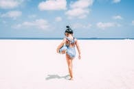 在阿鲁巴明亮的沙滩上，一个穿着泳衣的小女孩正享受着阳光明媚的一天