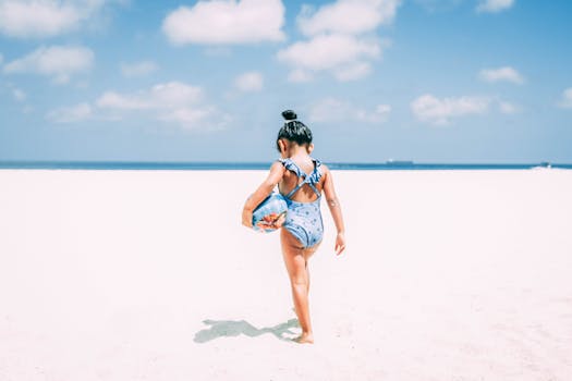 在阿鲁巴明亮的沙滩上，一个穿着泳衣的小女孩正享受着阳光明媚的一天