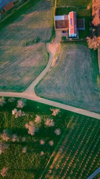 Stunning aerial view of rural Swiss farmland and farmhouse at sunset, showcasing natural beauty.