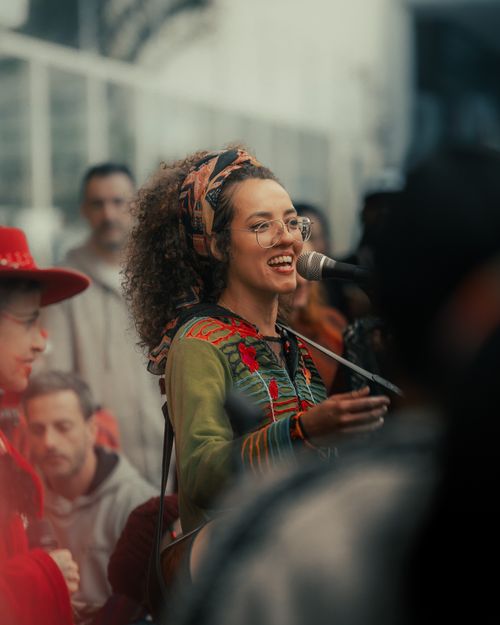 Free Vibrant street musician performing with a diverse crowd in an outdoor setting. Stock Photo