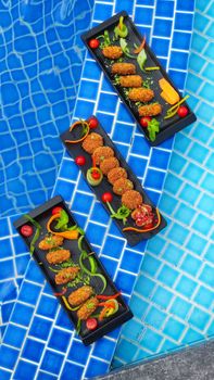 Crispy appetizers beautifully presented by the pool, perfect for summer gatherings.