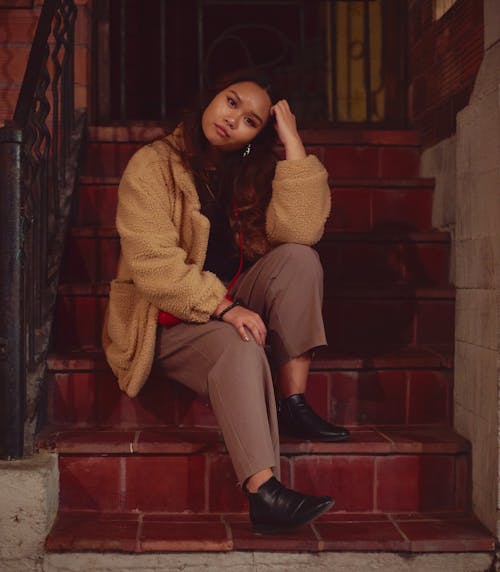 A Woman Wearing Coat Sitting on Stairs