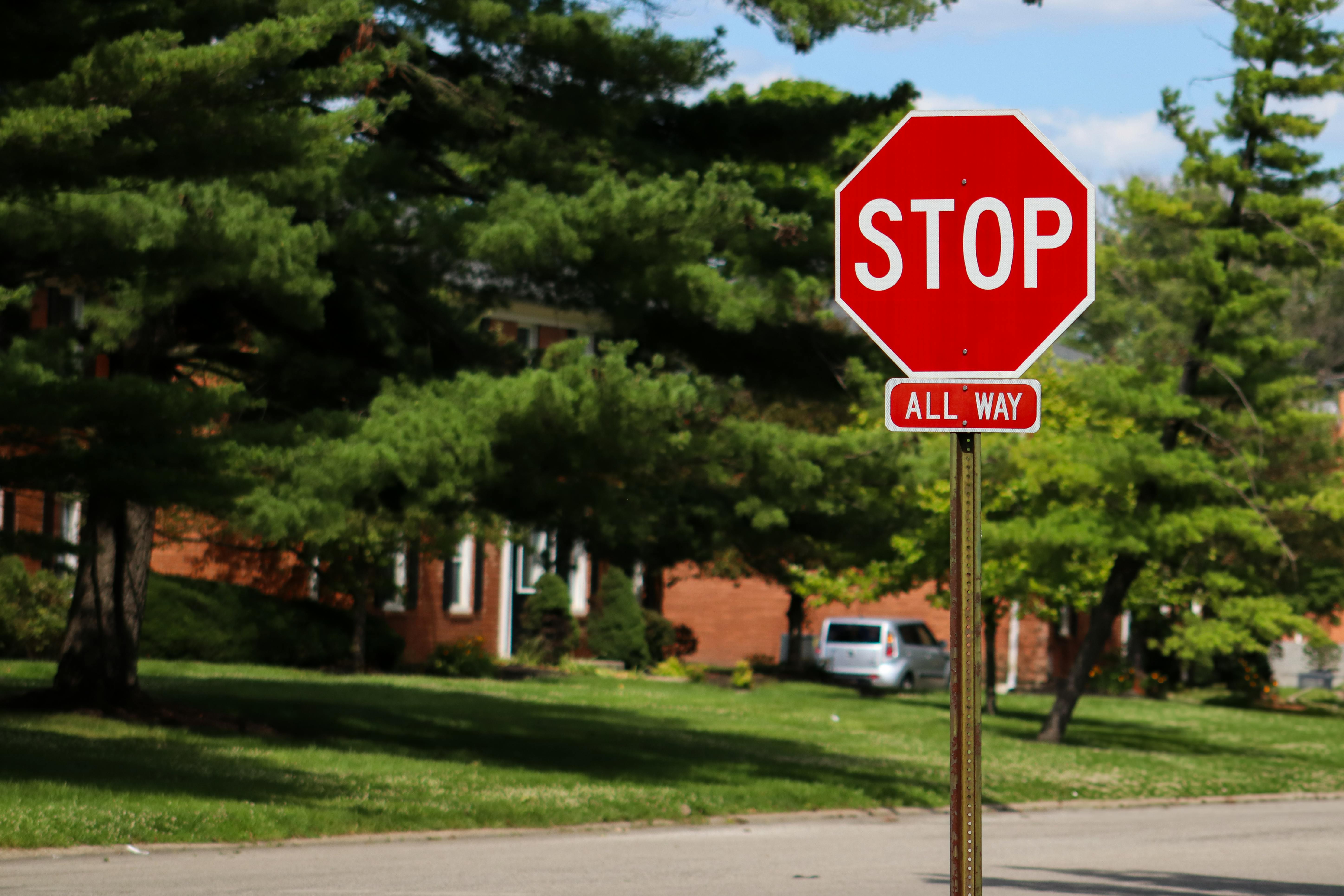 A stop sign on an Indianapolis street with suburban houses and lush green trees.