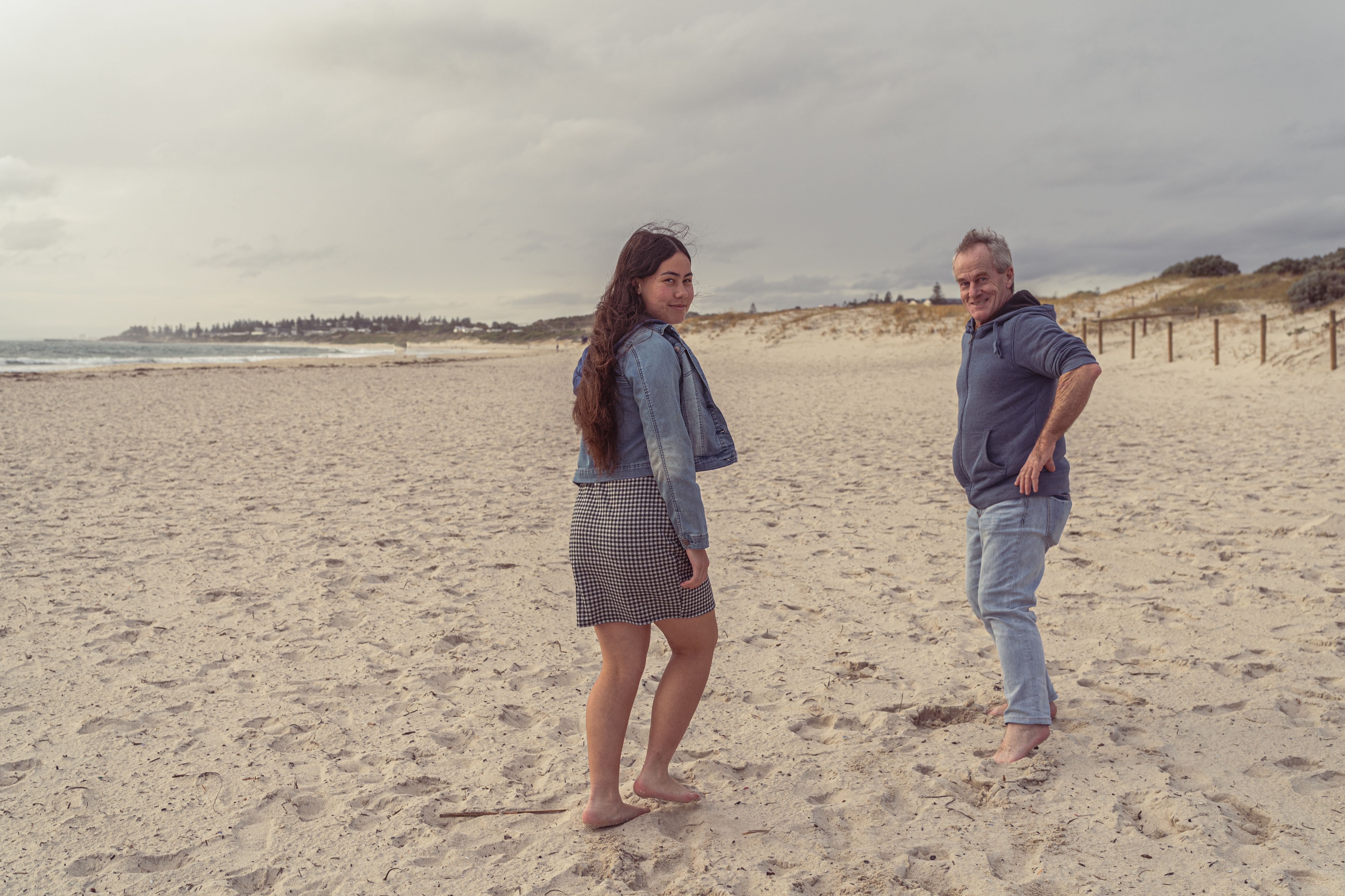 Father and daughter strolling along a quiet beach, light breeze and soft waves during spring