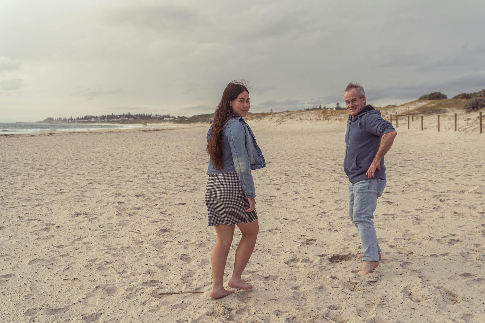 Father and daughter strolling along a quiet beach, light breeze and soft waves during spring